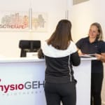 Eine Frau steht am Empfang Physiotherapiepraxis und spricht mit Inga Gehrken.